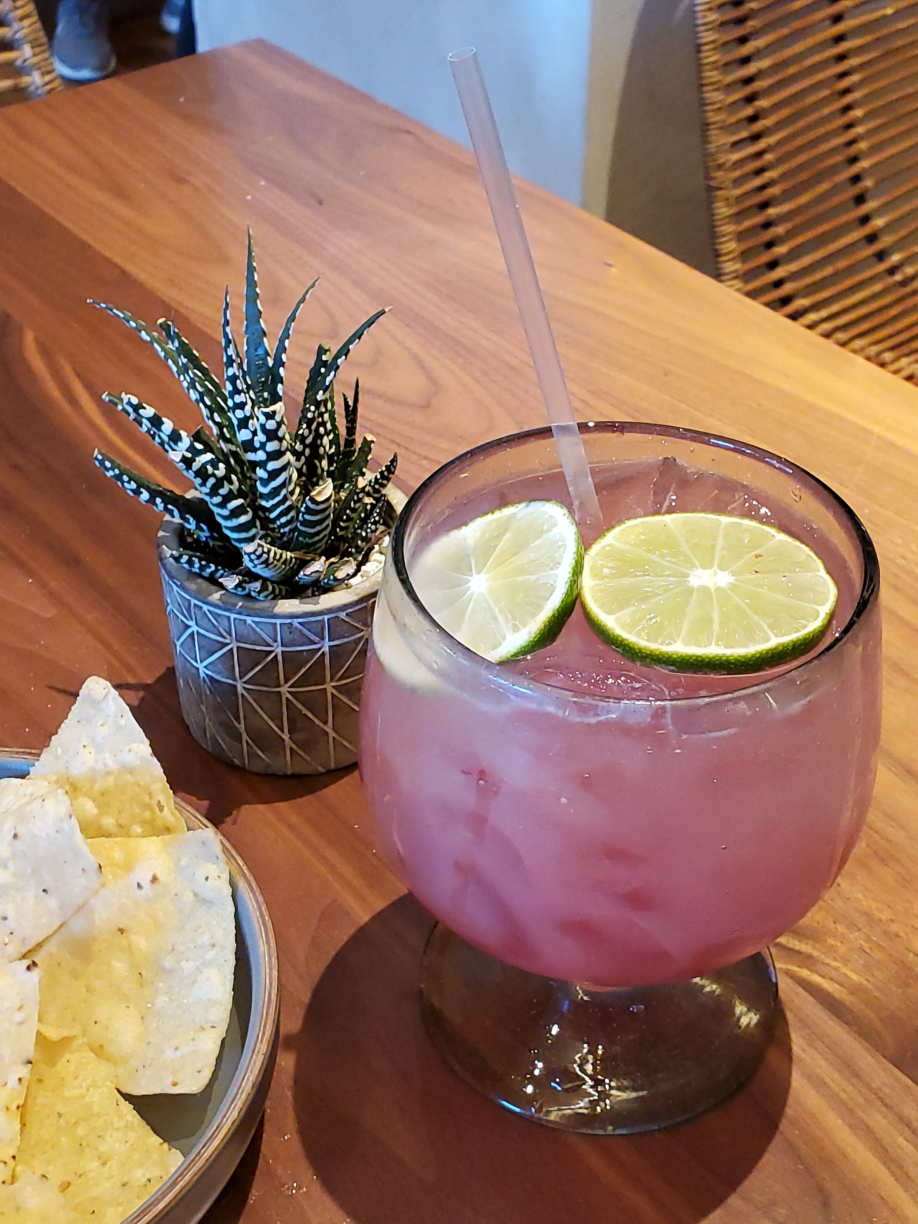 Large margarita glass with red drink and two lime slices